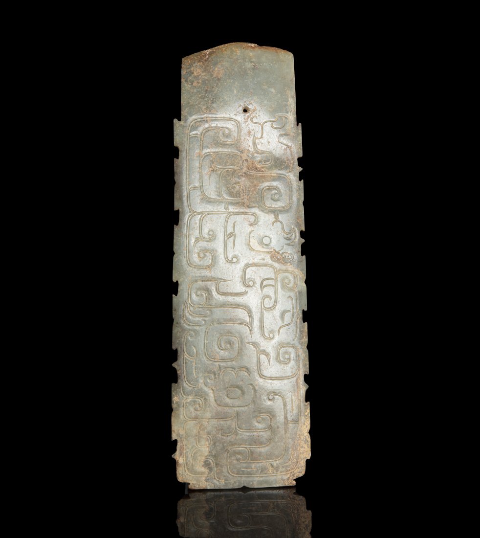 A ‘PHOENIX’ ARCHAISTIC CELADON AND RUSSETS: A â€˜PHOENIXâ€™ ARCHAISTIC CELADON AND RUSSETS JADE AXE Qing Dynasty or earlier Carved out of a single piece of pale celadon jade, both sides adorned with a coiled phoenix describing serpenti