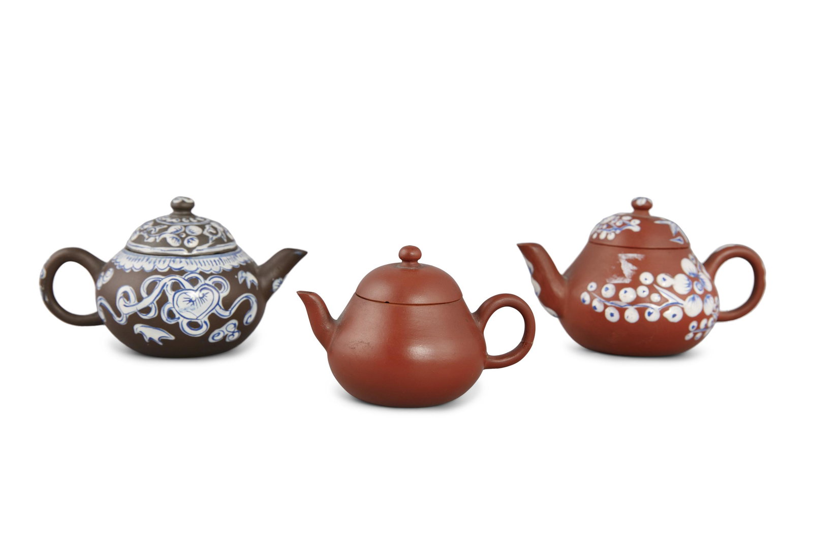 A GROUP OF THREE (3) YIXING TEAPOTS China, 20th century: A GROUP OF THREE (3) YIXING TEAPOTS China, 20th century The first one made of brown clay and enhanced with white and blue thick enamels depicting notably an artemisia leaf, the base with an impressed 