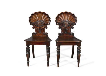 A PAIR OF GEORGE IV MAHOGANY HALL CHAIRS, the shell carved backs with painted cartouche with crest,: A PAIR OF GEORGE IV MAHOGANY HALL CHAIRS, the shell carved backs with painted cartouche with crest, solid seats and raised on turned fluted tapering legs