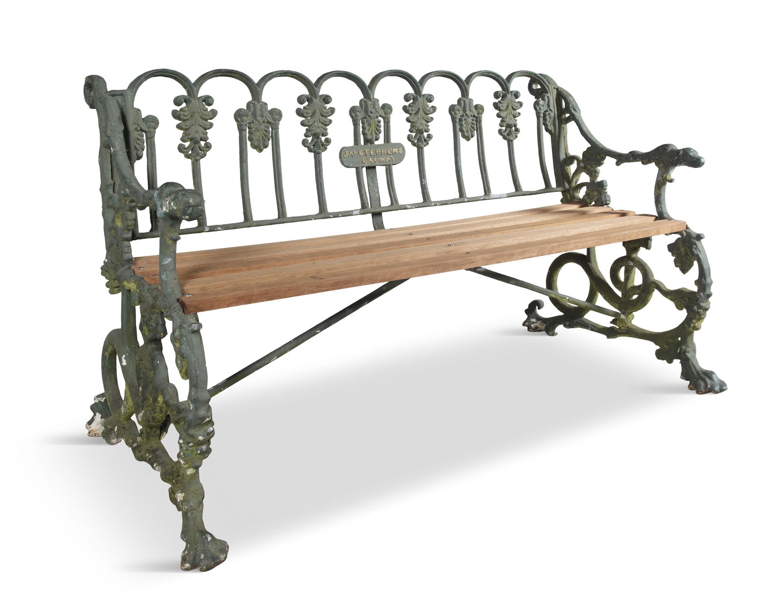 A VICTORIAN GREEN PAINTED CAST IRON GARDEN BENCH, probably Coalbrookdale, the arched back cast with: A VICTORIAN GREEN PAINTED CAST IRON GARDEN BENCH, probably Coalbrookdale, the arched back cast with anthemions and leaf scrolls, centred with a plaque 'James Stephens, Galway' with timber slatted seat