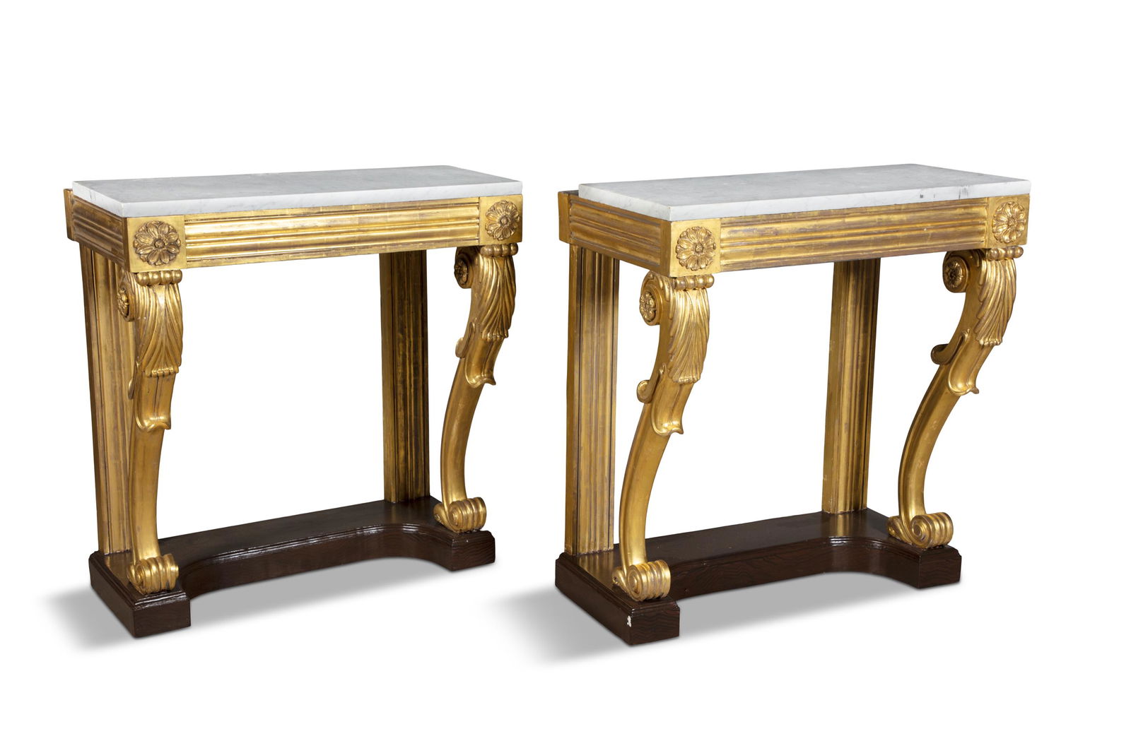A PAIR OF WILLIAM IV GILTWOOD CONSOLE TABLES, the moulded friezes raised on leaf carved scroll legs: A PAIR OF WILLIAM IV GILTWOOD CONSOLE TABLES, the moulded friezes raised on leaf carved scroll legs on mahogany platform bases. 90cm wide, 54cm deep, 97cm high