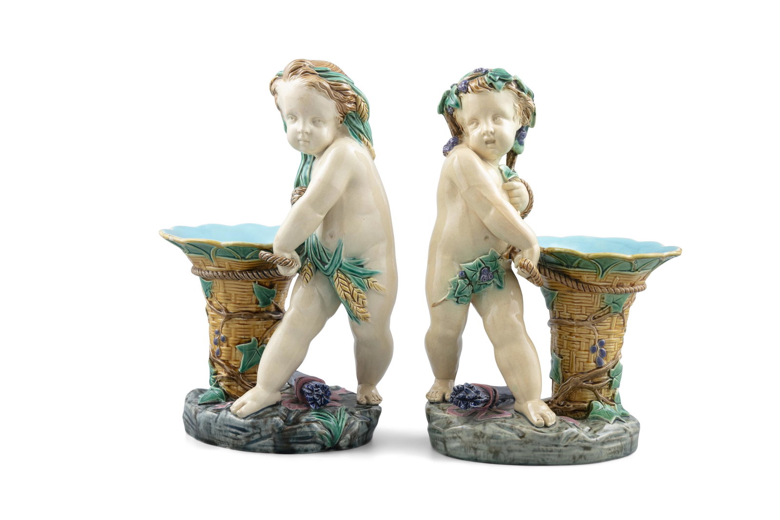 A VICTORIAN MINTON’S MAJOLICA GARNITURE comprising an oval reticulated basket and a pair of: A VICTORIAN MINTON’S MAJOLICA GARNITURE comprising an oval reticulated basket and a pair of vases modelled as putti, impressed marks . The basket 42cm wide; the vases 27cm high (3) *Please note 
