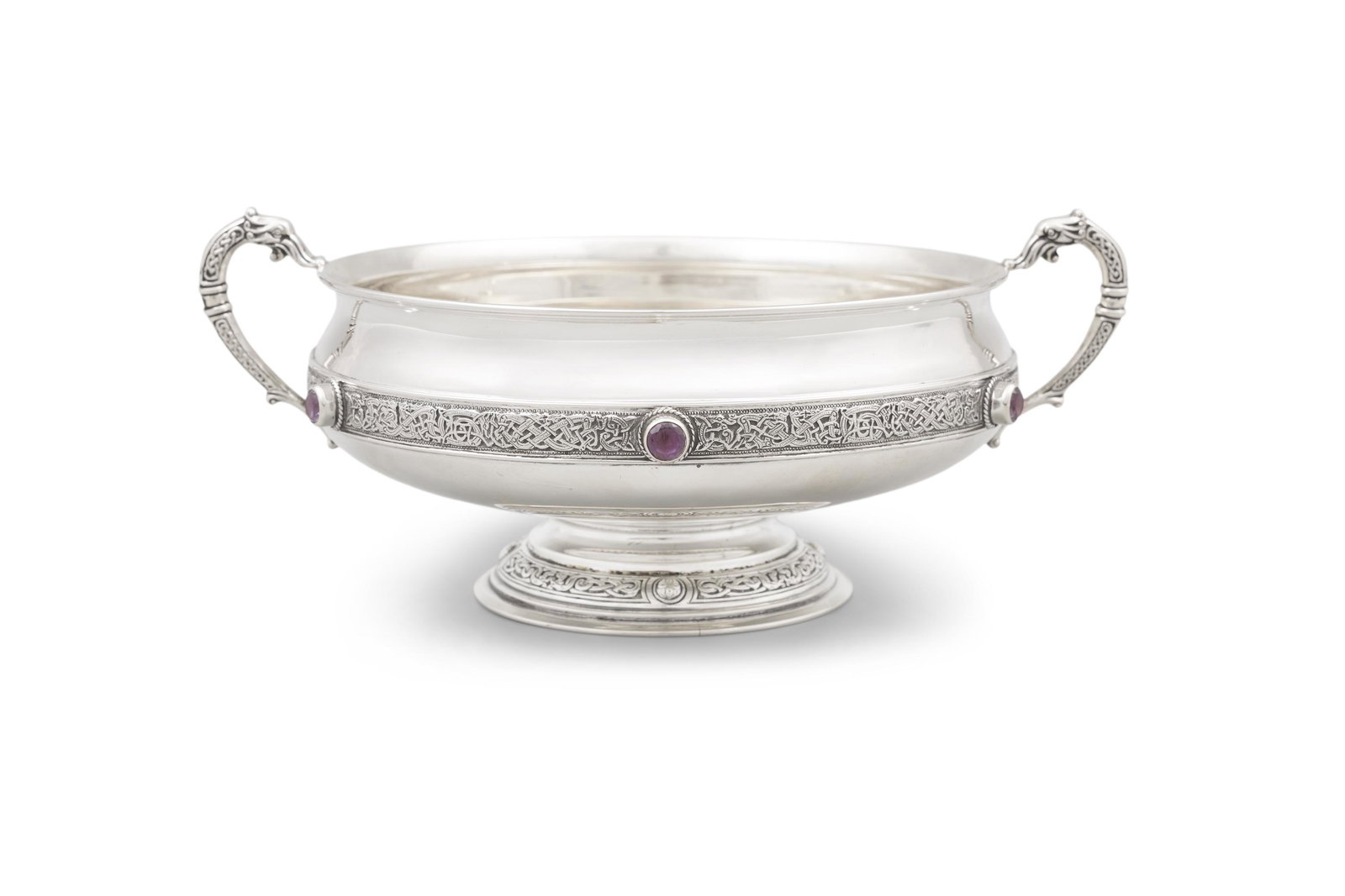 AN IRISH SILVER CELTIC BOWL, Dublin c.1924, mark of West & Sons, of circular form chased with: AN IRISH SILVER CELTIC BOWL, Dublin c.1924, mark of West & Sons, of circular form chased with bosses and bands of Celtic motifs, raised on spreading feet (24.94 troy ozs). 28cm wide across handles, 10