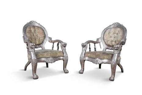 A PAIR OF ANGLO-INDIAN SILVER-WOOD UPHOLSTERED ARMCHAIRS, LATE 19TH CENTURY, the padded button: A PAIR OF ANGLO-INDIAN SILVER-WOOD UPHOLSTERED ARMCHAIRS, LATE 19TH CENTURY, the padded button backs with repoussÃ© silvered decoration and down-scrolling arms, with lion head terminals, serpentine