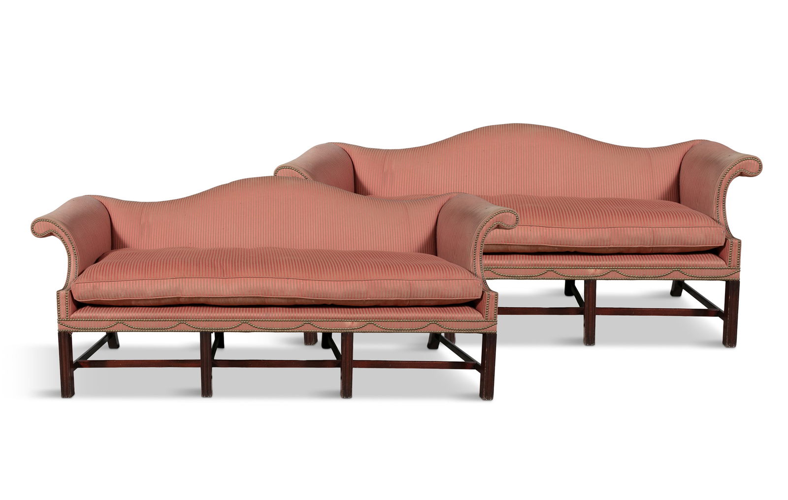 A PAIR OF GEORGE III MAHOGANY FRAMED HUMP BACK SETTEES, each with close nail red striped upholstery: A PAIR OF GEORGE III MAHOGANY FRAMED HUMP BACK SETTEES, each with close nail red striped upholstery, scroll-end arms and single loose squab cushion, the aprons with studded decoration, raised on squar