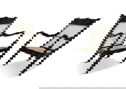 A PAIR OF 19TH CENTURY ANGLO-INDIAN CARVED EBONY SCROLL BACK ARMCHAIRS, the crest rails profusely: A PAIR OF 19TH CENTURY ANGLO-INDIAN CARVED EBONY SCROLL BACK ARMCHAIRS, the crest rails profusely covered with scallop shell and leaf sprays, echoed in the arms and seat rail, having caned backs and s