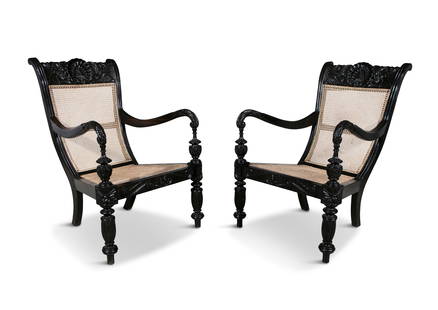 A PAIR OF 19TH CENTURY ANGLO-INDIAN CARVED EBONY SCROLL BACK ARMCHAIRS, the crest rails profusely : A PAIR OF 19TH CENTURY ANGLO-INDIAN CARVED EBONY SCROLL BACK ARMCHAIRS, the crest rails profusely covered with scallop shell and leaf sprays, echoed in the arms and seat rail, having caned backs and s