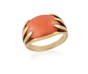 A CORAL DRESS RING, BY CARTIER The oval-shaped corallium rubrum coral cabochon within a six-claw: A CORAL DRESS RING, BY CARTIER The oval-shaped corallium rubrum coral cabochon within a six-claw setting, mounted in 18K gold, signed Cartier, ring size K¾