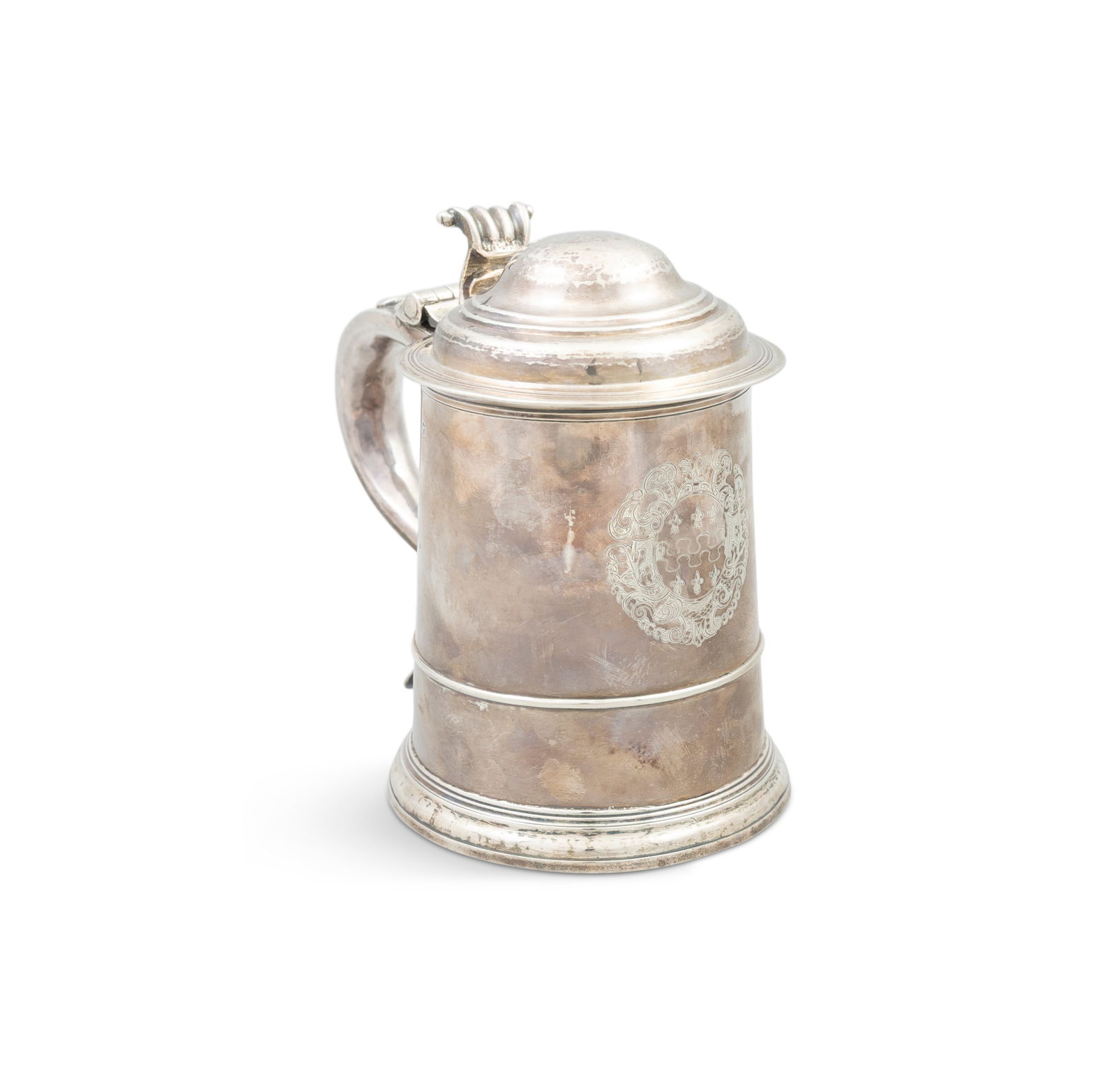 A LARGE GEORGE I SILVER TANKARD, London c.1718, maker's mark of Thomas Mann, the domed lid with: A LARGE GEORGE I SILVER TANKARD, London c.1718, maker's mark of Thomas Mann, the domed lid with scrolled thumb-piece on plain tapering body with a ribbed banding, scroll handle, contemporary coat of a