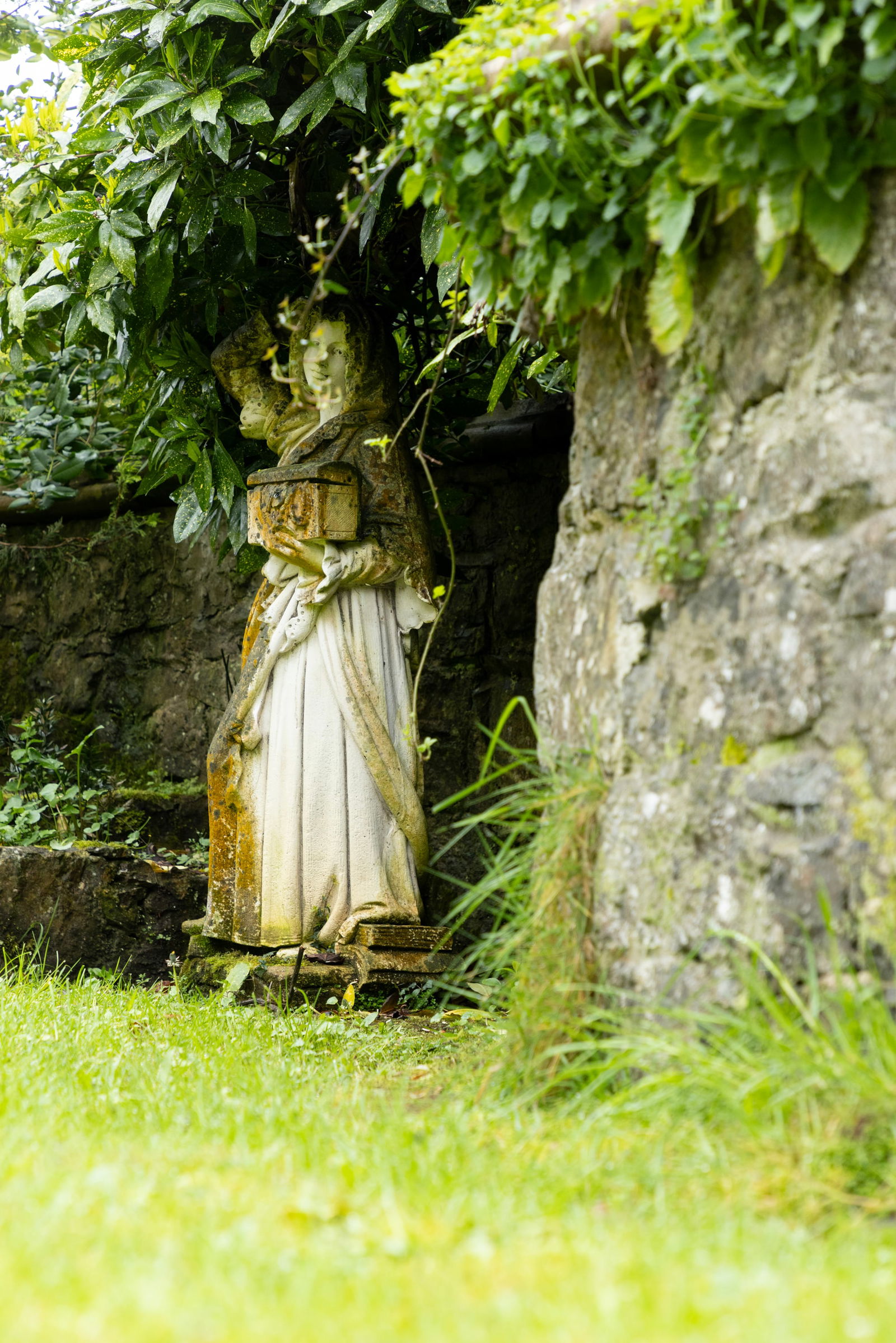 A LARGE STONE COMPOSITE FIGURE OF A STANDING MAIDEN, 20TH CENTURY,   holding a casket on a square (1 of 2)