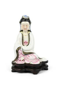 A FAMILLE ROSE FIGURE OF GUANYIN WITH WOOD STAND, MARKED QIANLONG ON THE REVERSE. __ ______ China,: A FAMILLE ROSE FIGURE OF GUANYIN WITH WOOD STAND, MARKED QIANLONG ON THE REVERSE. __ ______ China, Republic period. Modelled in seated position wearing a fastened robe with black and gilt trim, with l