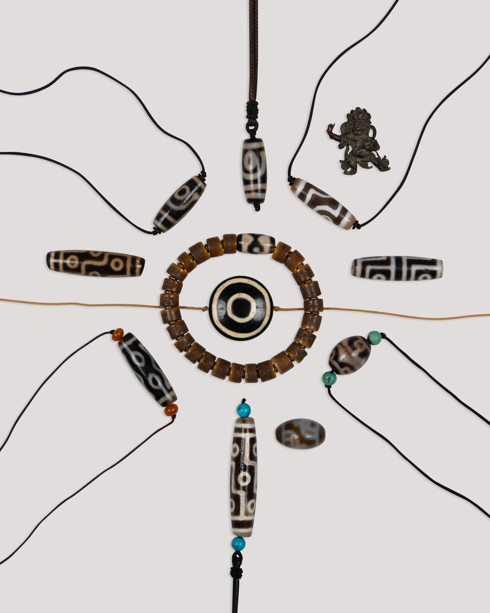 A COLLECTION OF TEN DZI BEADS, WITH A BONE AND DZI BEADS BRACELET AND A SMALL BRONZE JAMBHALA __: A COLLECTION OF TEN DZI BEADS, WITH A BONE AND DZI BEADS BRACELET AND A SMALL BRONZE JAMBHALA __ 20__ ______________ Tibet, 20th century L(dzi).2.2-5.9cm L.(bracelet bead)0.7-1.9cm H.(jambhala)3cm