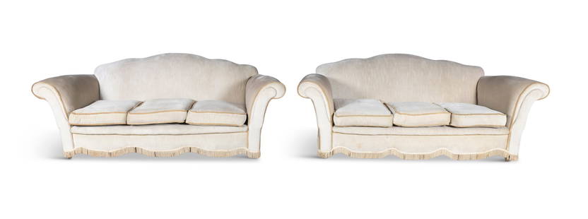 A PAIR OF BEIGE UPHOLSTERED THREE-SEATER SOFAS, each with outscrolled arms and loose seat: A PAIR OF BEIGE UPHOLSTERED THREE-SEATER SOFAS, each with outscrolled arms and loose seat cushions, 80cm high, 217cm wide, 95cm deep