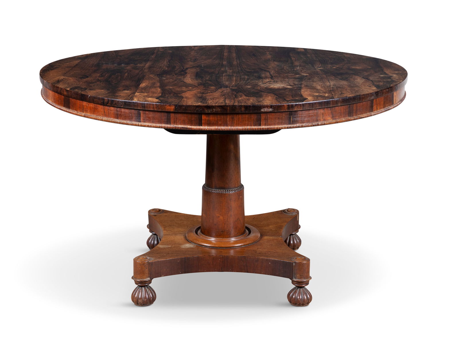 AN GEORGE IV ROSEWOOD BREAKFAST TABLE, the plain solid top with moulded edge on a heavy tapering: AN GEORGE IV ROSEWOOD BREAKFAST TABLE, the plain solid top with moulded edge on a heavy tapering centre column, on concave platform base with roundels and raised on fluted bun feet. 78cm high, 120cm d