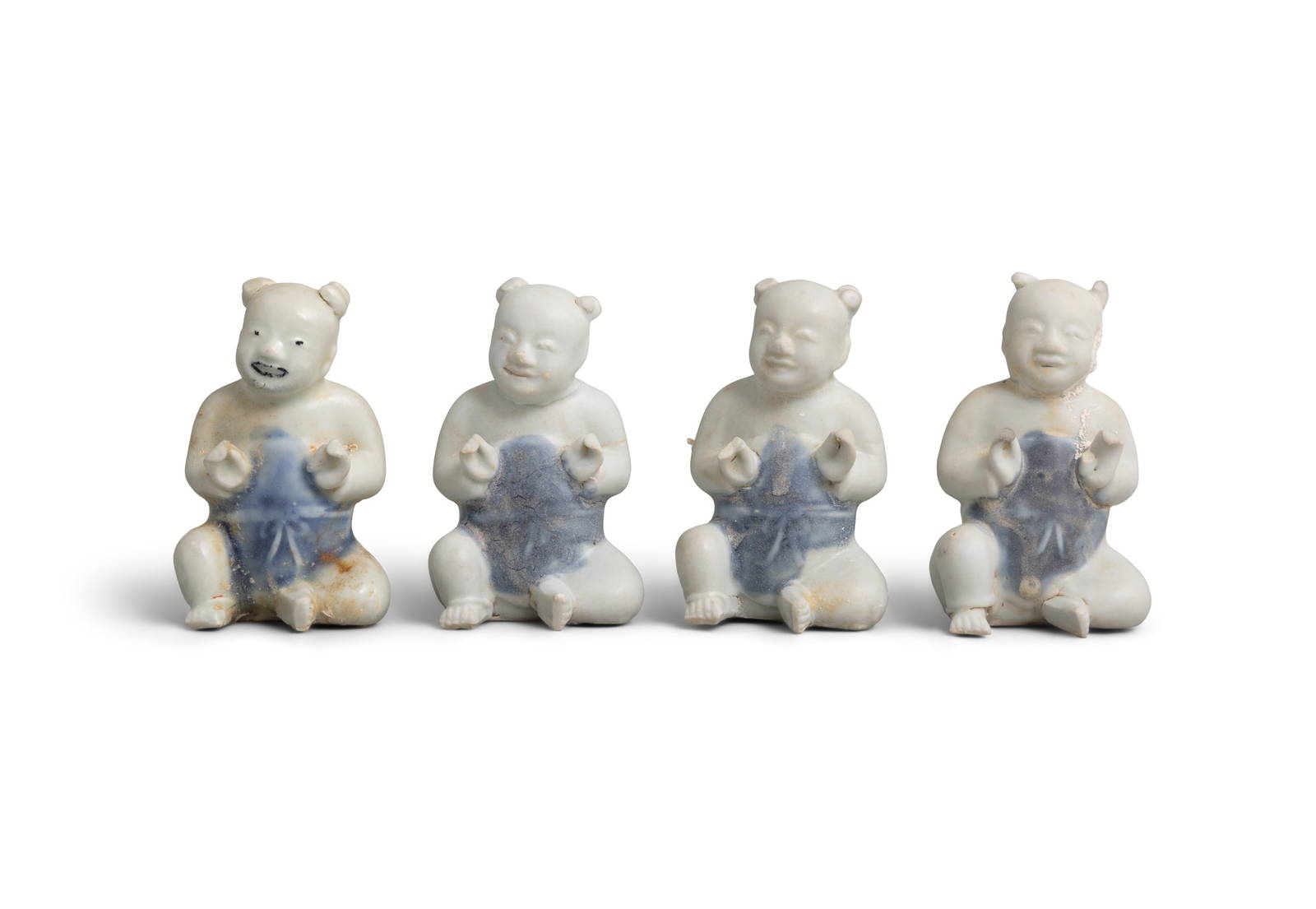 FOUR FIGURES OF A SEATED BOY China, Yongzheng period, circa 1725 Wearing a short blue-glazed