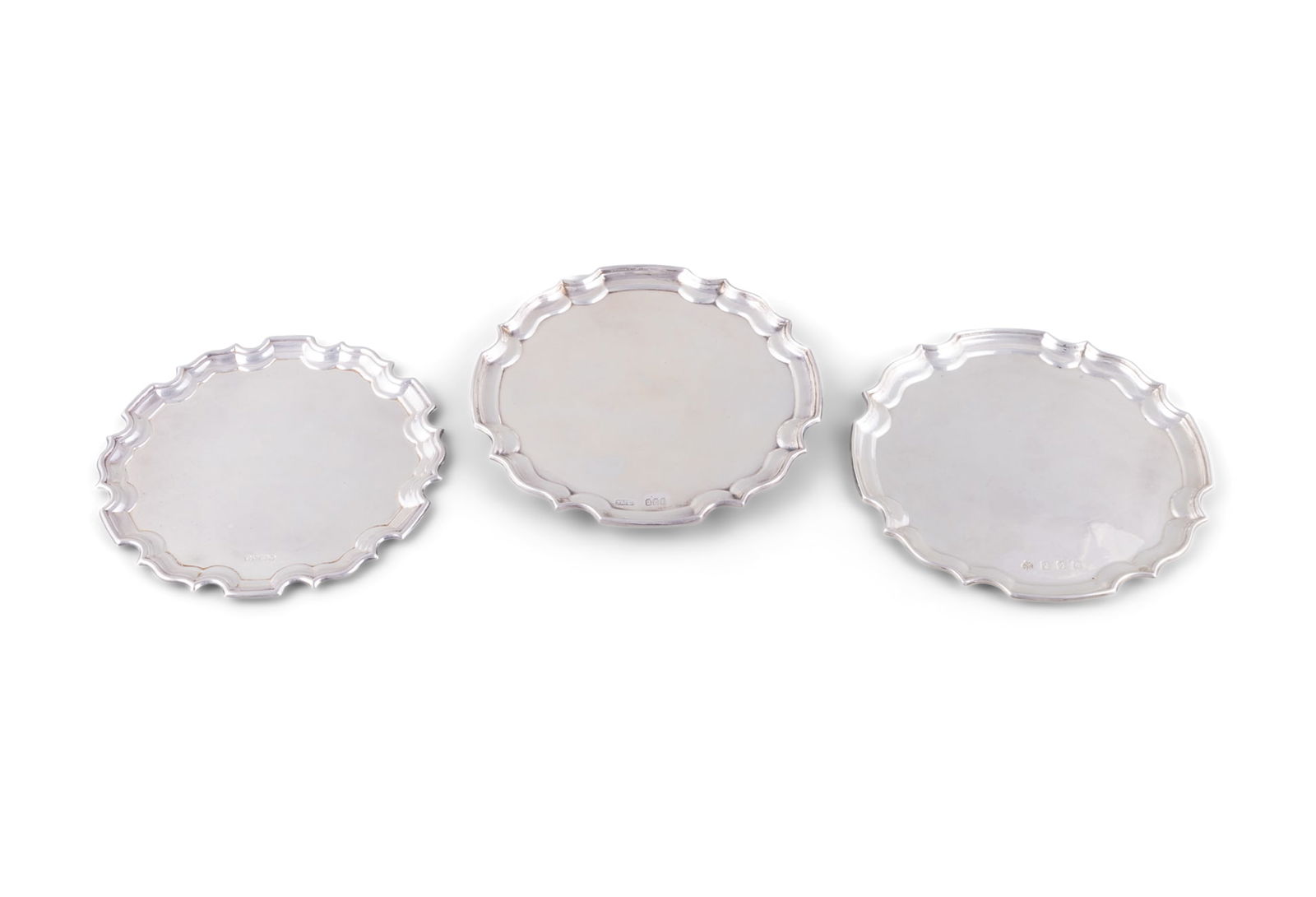 A COLLECTION OF THREE SILVER CARD TRAYS, 20TH CENTURY, each of various dates and makers, of: A COLLECTION OF THREE SILVER CARD TRAYS, 20TH CENTURY, each of various dates and makers, of circular form, with raised pie crust rims, one raised on three short legs (c.14.9 troy ozs). Each c.15.5cm d