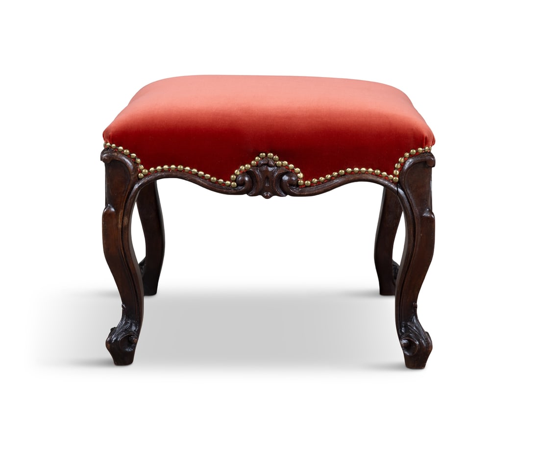 A VICTORIAN MAHOGANY FRAMED RECTANGULAR STOOL covered in a red seat fabric with brass studding, on: A VICTORIAN MAHOGANY FRAMED RECTANGULAR STOOL covered in a red seat fabric with brass studding, on cabriole legs and leaf carved feet 40cm high x 49cm wide