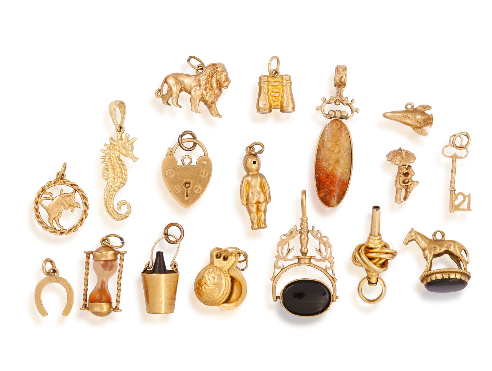 A GROUP OF CHARMS Comprising seventeen charms, including: a bucket with a wine bottle, a small chi: A GROUP OF CHARMS Comprising seventeen charms, including: a bucket with a wine bottle, a small child, a heart-shaped padlock, a swivel fob set with a black chalcedony and tiger’s eye, a pendant