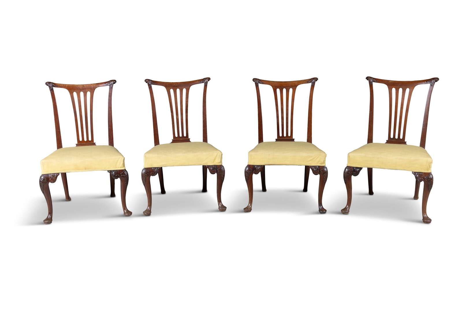 A SET OF FOUR IRISH GEORGE III CARVED MAHOGANY SIDE CHAIRS, each with dipped toprail and leaf: A SET OF FOUR IRISH GEORGE III CARVED MAHOGANY SIDE CHAIRS, each with dipped toprail and leaf carved corners, above a four-bar open splat and upholstered seat, in pale green, on leaf capped cabriole l