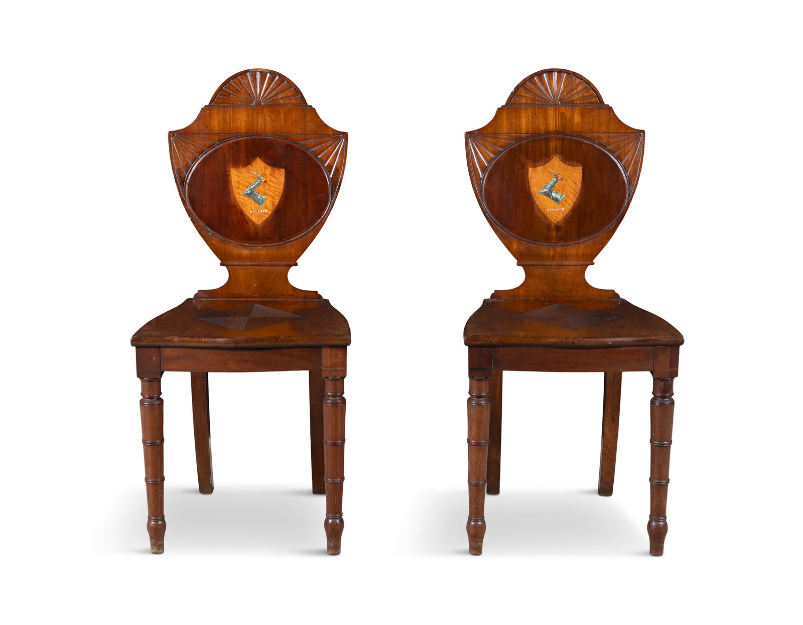 A PAIR OF GEORGE IV MAHOGANY ARMORIAL HALL CHAIRS, each with shield backs and half patera design (1 of 7)