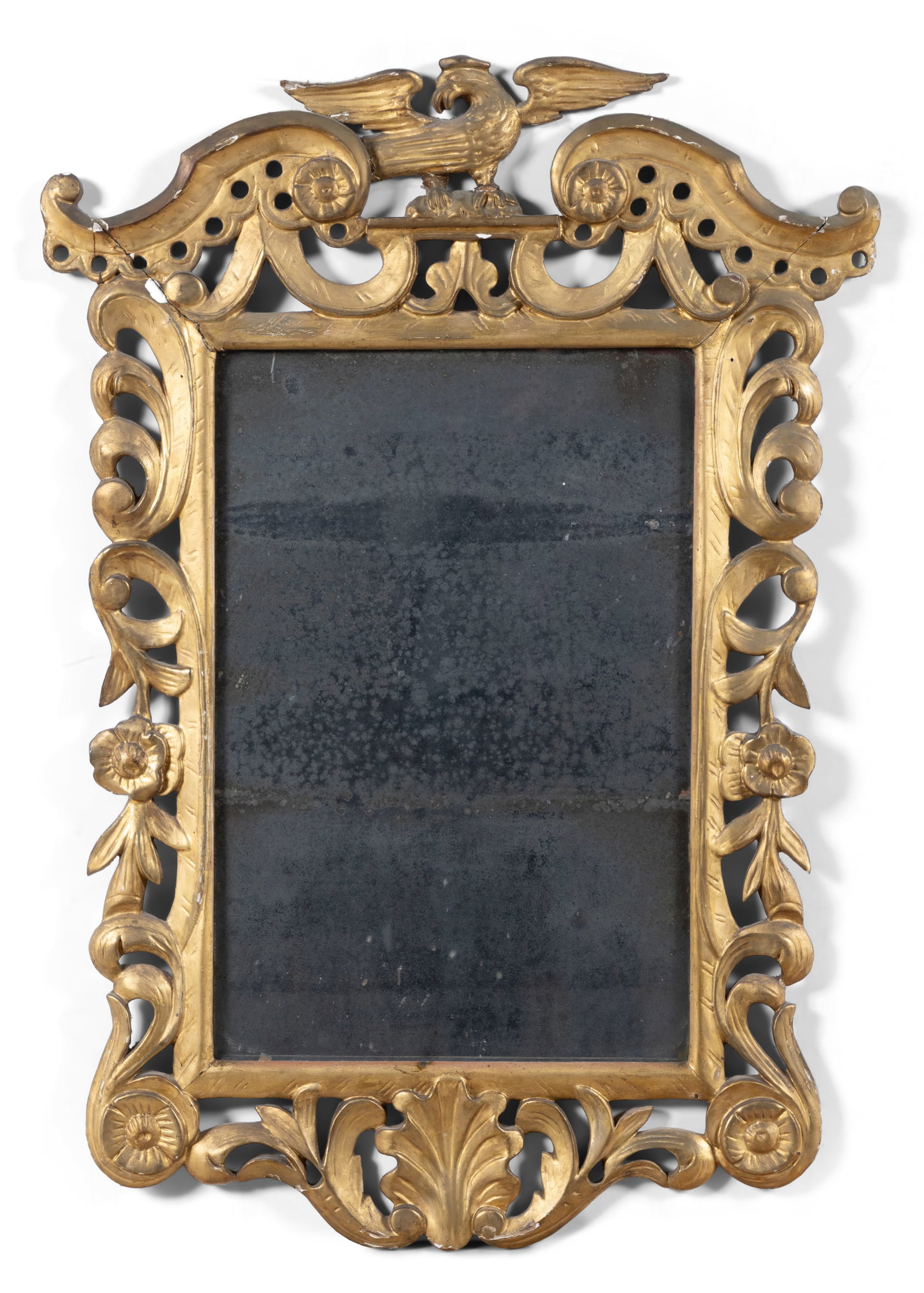 AN IRISH GEORGE III GILTWOOD WALL MIRROR, the carved giltwood frame surmounted by an eagle and: AN IRISH GEORGE III GILTWOOD WALL MIRROR, the carved giltwood frame surmounted by an eagle and comprising of large C-scrolls and flower heads, enclosing the mirror plate above a carved scallop shell t