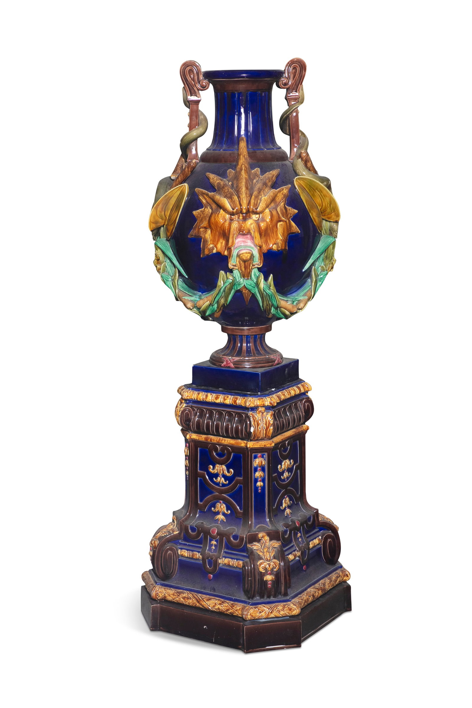 A LARGE SARREGUEMINES MAJOLICA URN AND PEDESTAL BY ALEXANDER DE GEIGER (1801-1891) & PAUL DE GEIGER: A LARGE SARREGUEMINES MAJOLICA URN AND PEDESTAL BY ALEXANDER DE GEIGER (1801-1891) & PAUL DE GEIGER (1837-1913) C.1880 - 1890 the urn with stylised sunburst lion heads to either side, decorated with s