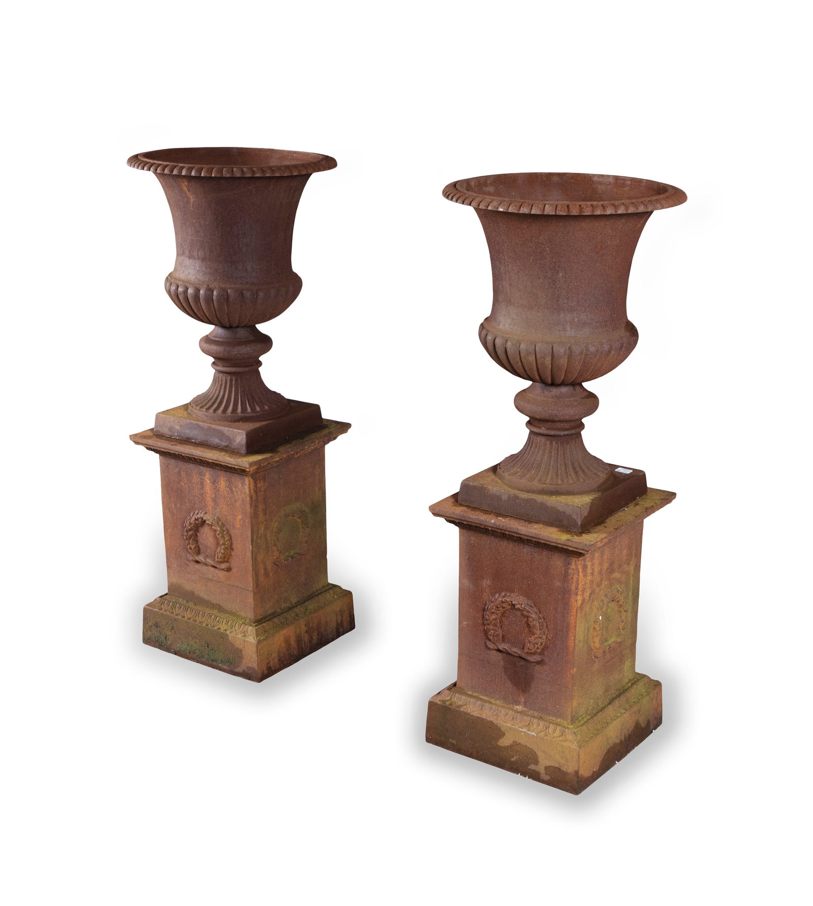 A PAIR OF CAST IRON GARDEN URNS of campagna form, with outturned rims, baluster demi-fluted: A PAIR OF CAST IRON GARDEN URNS of campagna form, with outturned rims, baluster demi-fluted bodies, each raised on waisted socle and plinth base, raised on square pedestal bases with ribbon tied swags