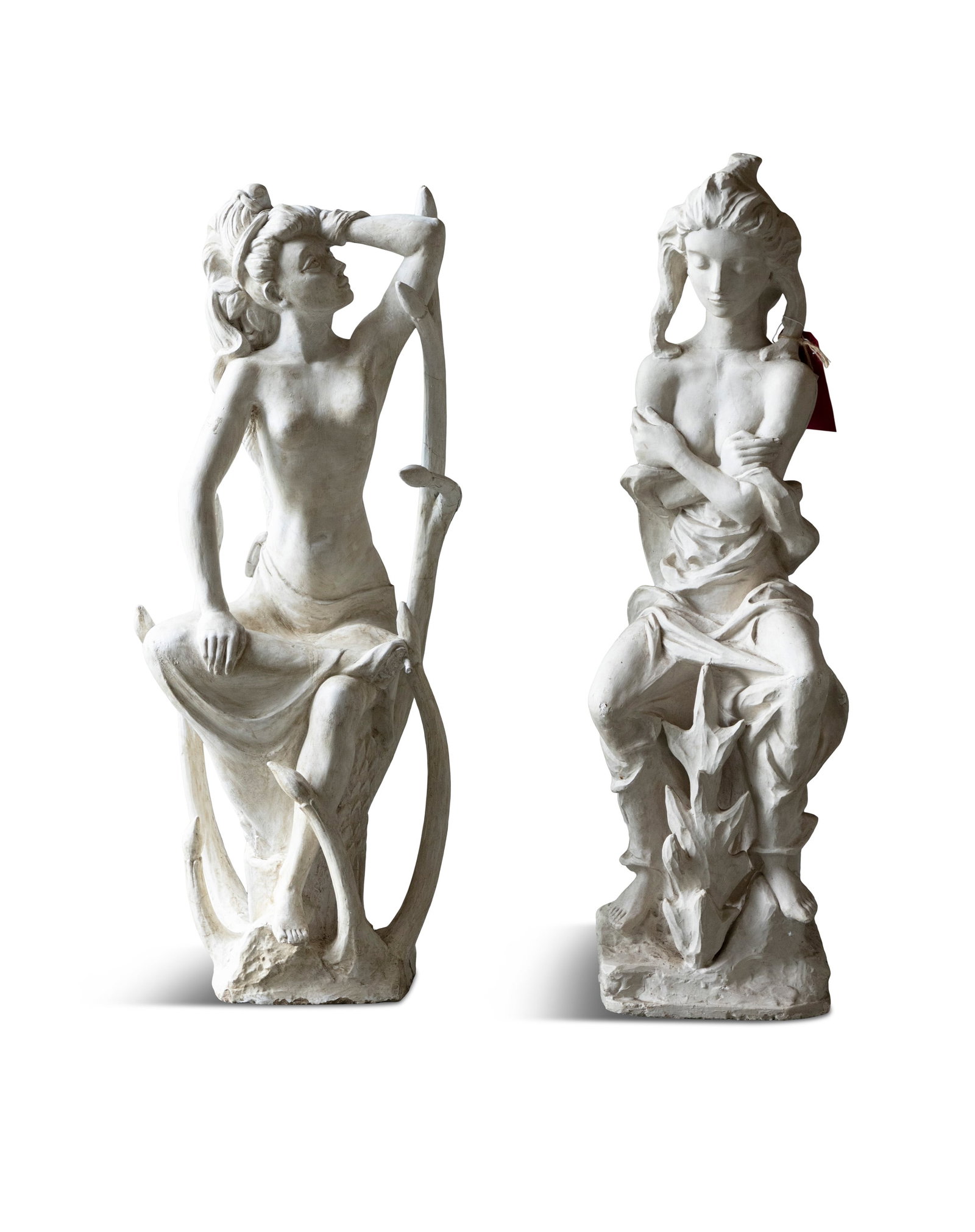 A PAIR OF COMPOSITE STONE FEMALE FIGURES, both modelled seated, on naturalistic tree slump bases, (1 of 4)