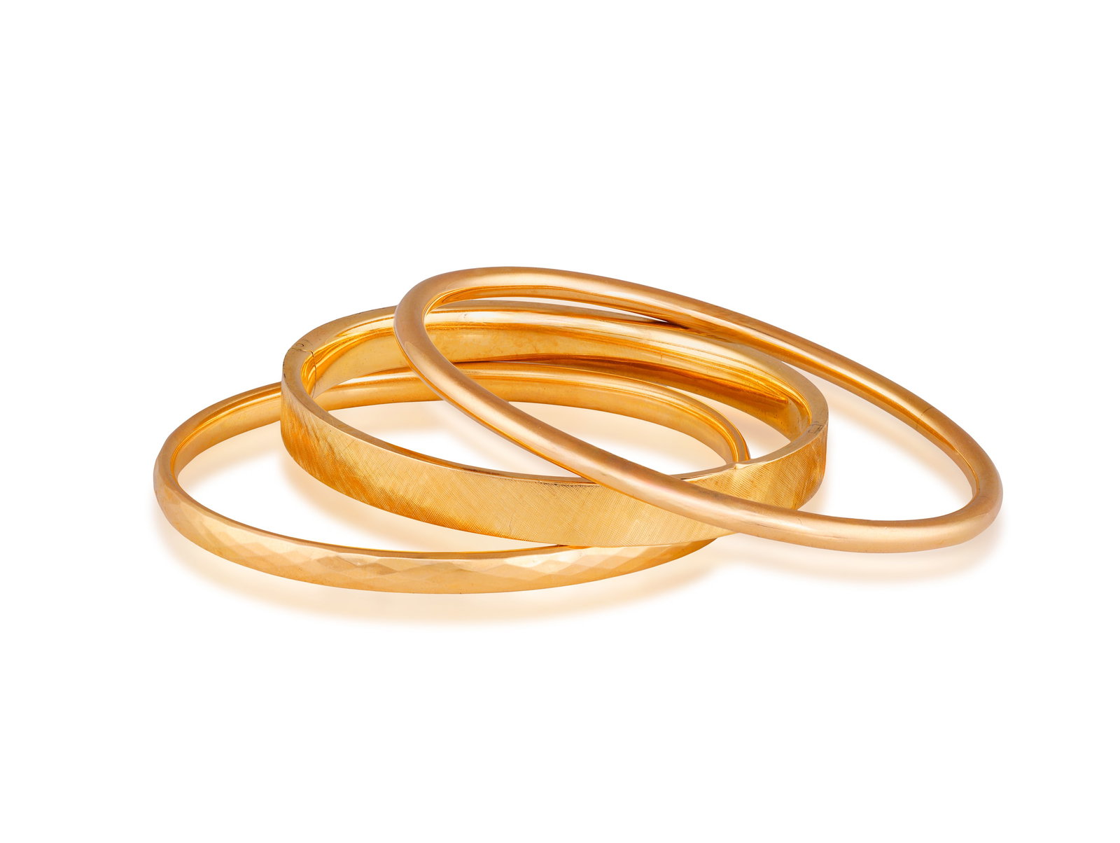 A GROUP OF THREE GOLD BANGLES • Three polished and textured bangles • each in 14K gold (1 of 2)