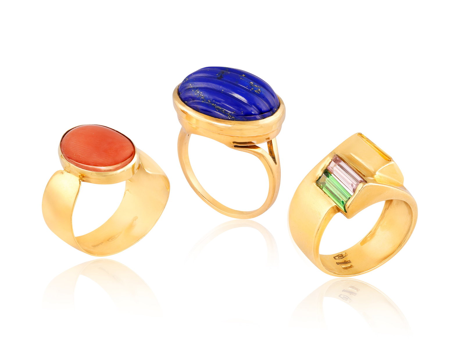 A GROUP OF THREE RINGS • The first carved oval-shaped lapis lazuli cabochon • mounted in: A GROUP OF THREE RINGS • The first carved oval-shaped lapis lazuli cabochon • mounted in 18K gold • ring size Q; The second ring • oval-shaped cabochon coral • mounted in 18K 