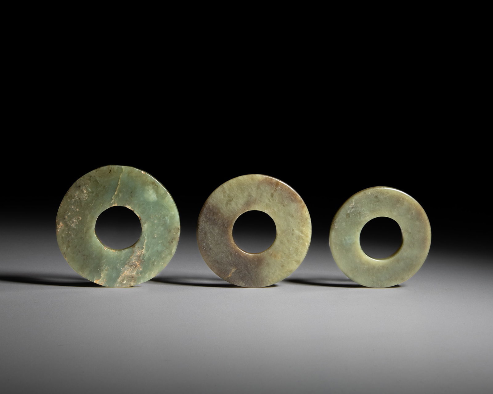 A COLLECTION OF THREE CELADON JADE BI 文化期 青玉璧一: A COLLECTION OF THREE CELADON JADE BI 文化期 青玉璧一组三件 China, Neolithic period OD.6.5-7.3cm Provenance: A Paris art instructor’s 