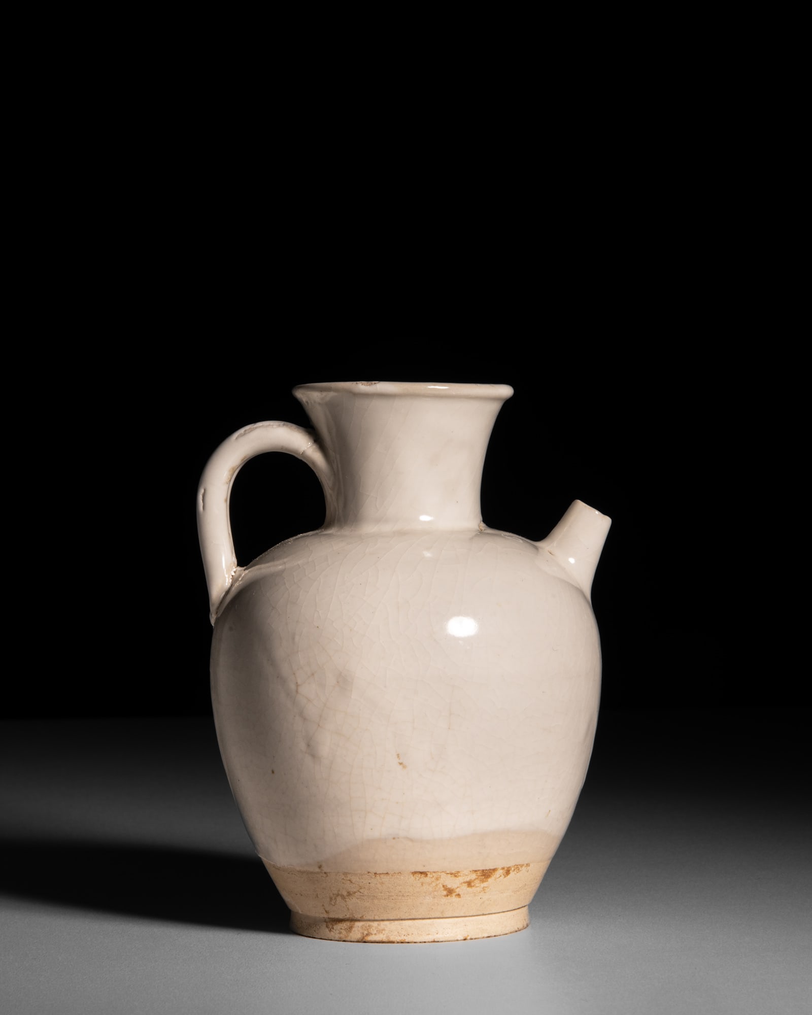 A WHITE-GLAZED EWER 唐代 白釉执壶 China, Tang dynasty: A WHITE-GLAZED EWER 唐代 白釉执壶 China, Tang dynasty (618-907) the well-proportioned body with a flared rim and constricted neck, tapering down to generous broad s