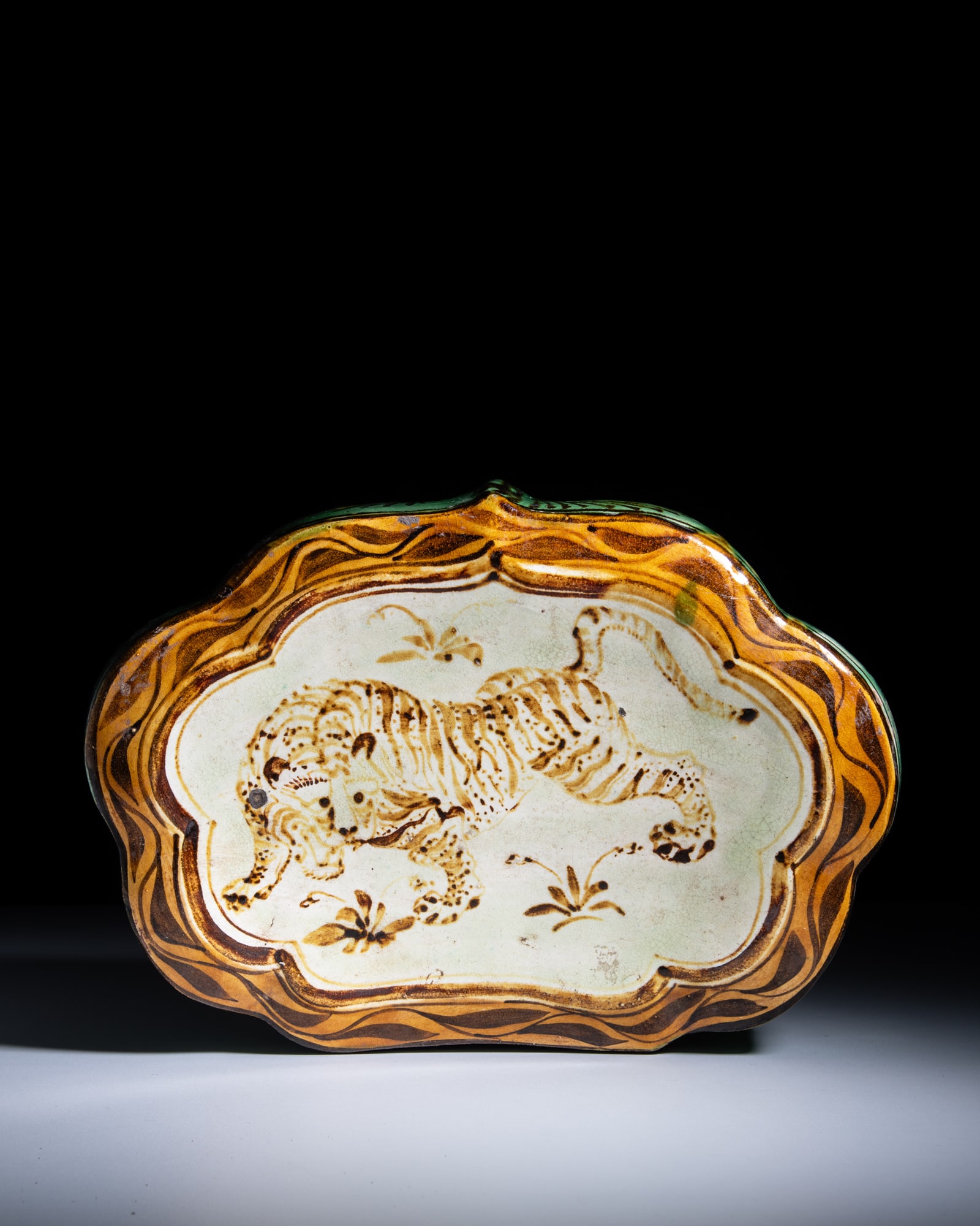 A YELLOW AND GREEN GLAZED CIZHOU 'TIGER' PILLOW, INCISED 'ZHANG JIA ZAO, GU XIANG' 明代: A YELLOW AND GREEN GLAZED CIZHOU 'TIGER' PILLOW, INCISED 'ZHANG JIA ZAO, GU XIANG' 明代 '古相、张家造‘刻款