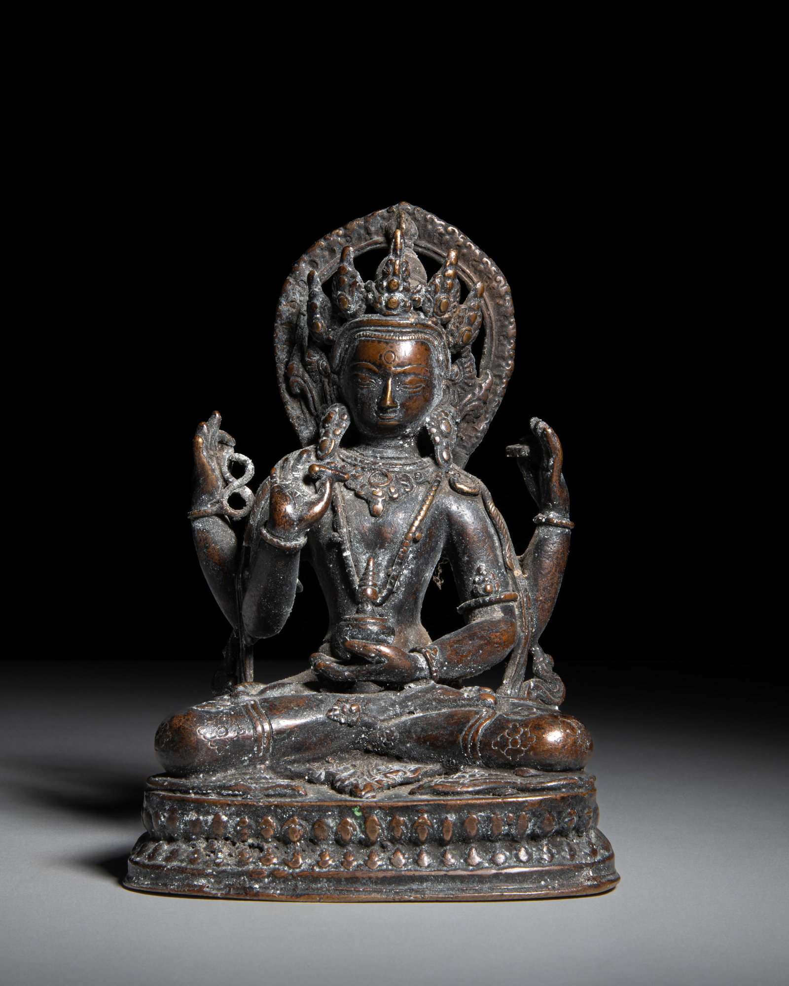 A DARK BRONZE FIGURE OF A FOUR ARMS CROWNED AMITAYUS Nepal, 20th century depicts Amitayus, the (1 of 3)