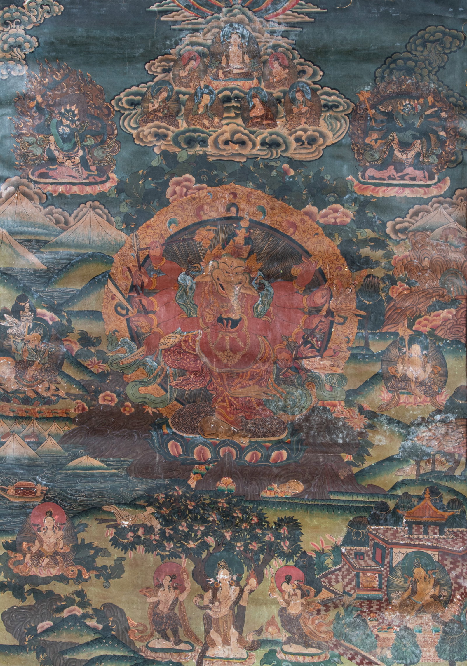 A LARGE POLYCHROME THANGKA ON CLOTH WITH A TWELVE-ARMED DANCING GANESHA Nepal, 20th Century With a: A LARGE POLYCHROME THANGKA ON CLOTH WITH A TWELVE-ARMED DANCING GANESHA Nepal, 20th Century With a green silk brocade framing At the center of the composition is the wrathful deity Red Ganapati (the R