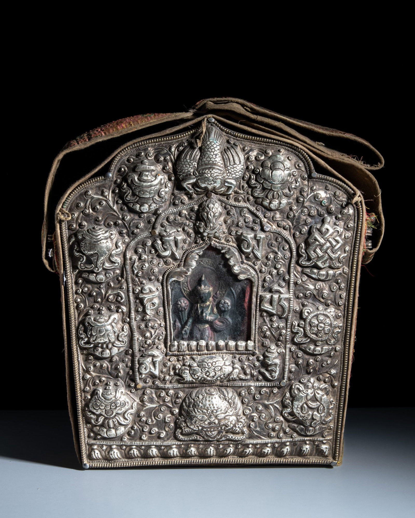 A LARGE BUDDHIST WHITE METAL PORTABLE SHRINE GAU ENCLOSED IN A SILK CLOTH POUCH Tibet or Nepal, (1 of 2)