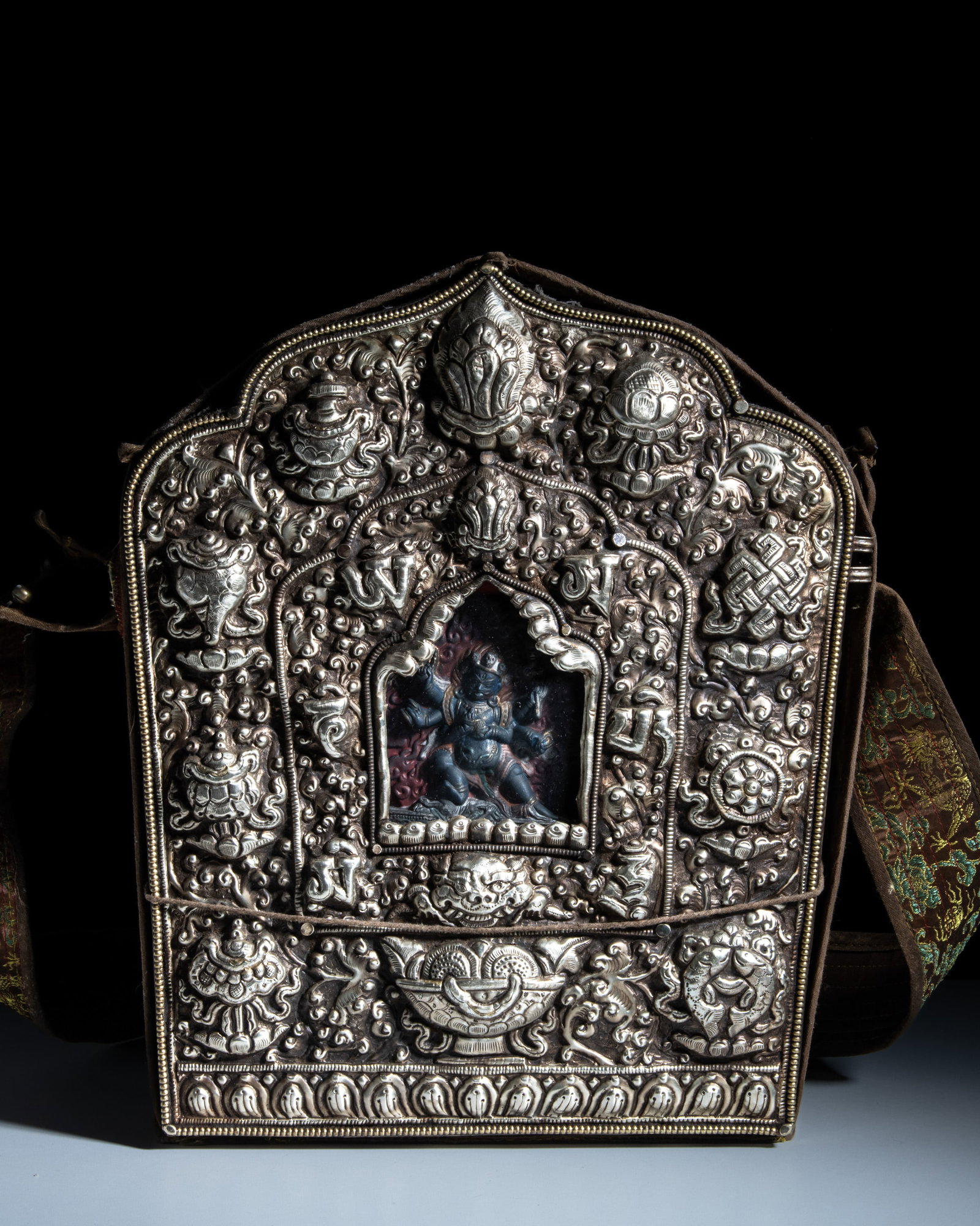 A LARGE BUDDHIST WHITE METAL PORTABLE SHRINE GAU ENCLOSED IN A SILK CLOTH POUCH Tibet or Nepal, (1 of 2)