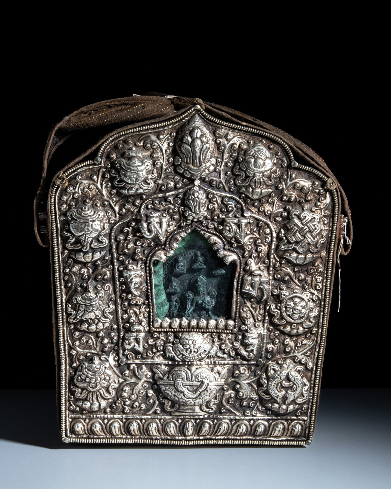 A LARGE BUDDHIST WHITE METAL PORTABLE SHRINE GAU ENCLOSED IN A SILK CLOTH POUCH Tibet or Nepal, (1 of 2)
