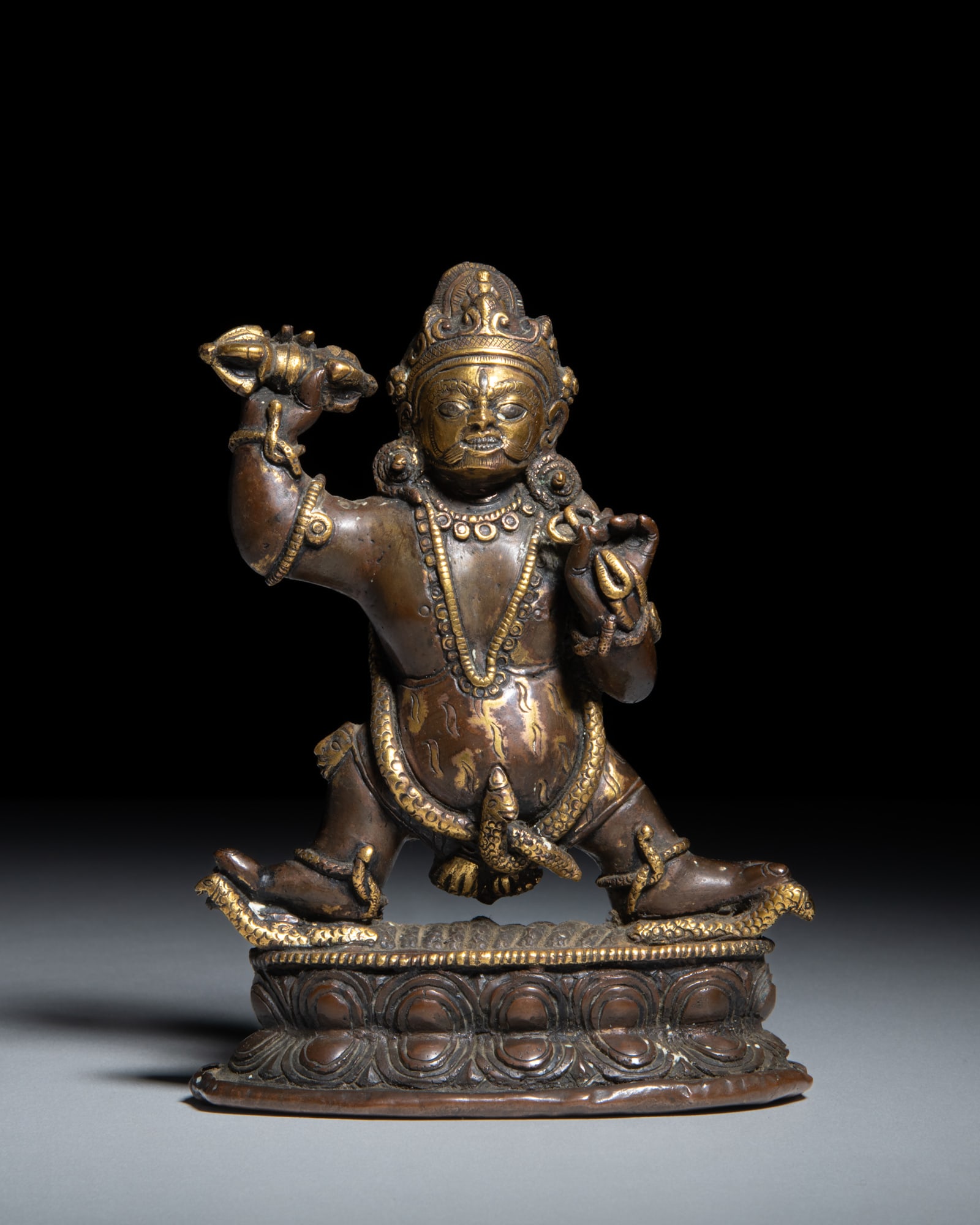 A PARTIALLY GILT-BRONZE FIGURE OF A VAJRAPANI Nepal-Tibet, late 19th-early 20th century depicts: A PARTIALLY GILT-BRONZE FIGURE OF A VAJRAPANI Nepal-Tibet, late 19th-early 20th century depicts the wrathful Bodhisattva Vajrapani standing in the dynamic pratyalidha warrior posture upon a beaded ova
