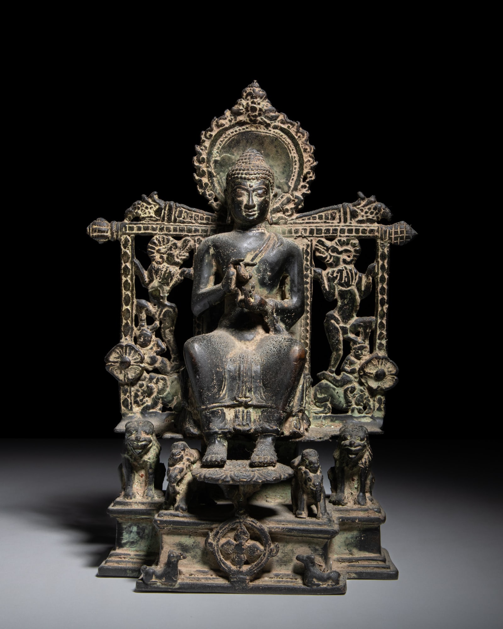 A BRONZE FIGURE OF A HALOED BUDDHA Indonesia, 20th Century The intricately cast bronze figure (1 of 3)