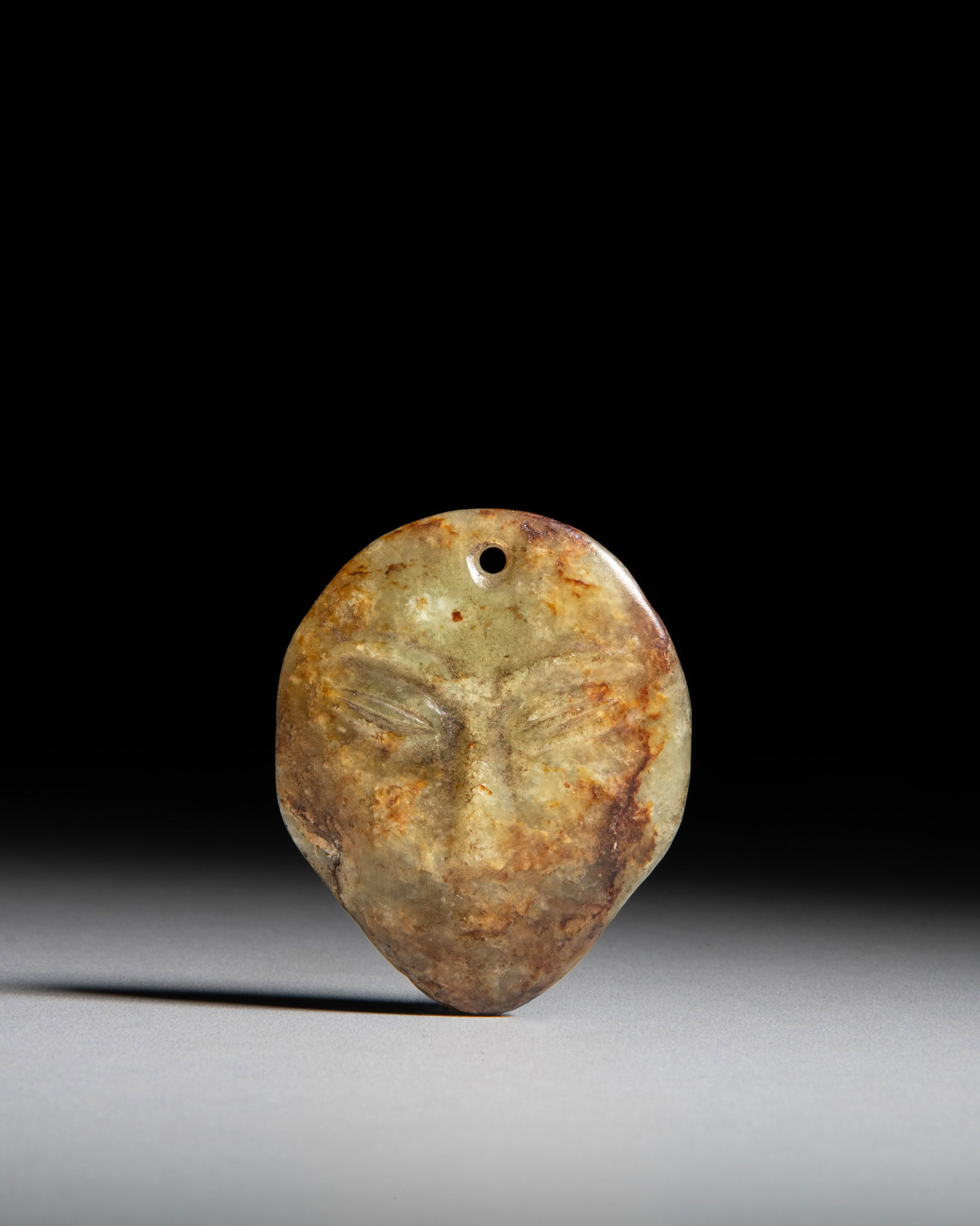 A YELLOW JADE PENDANT CARVED AS A HUMAN MASK WITH RUSSET INCLUSIONS 红山文化 (1 of 2)