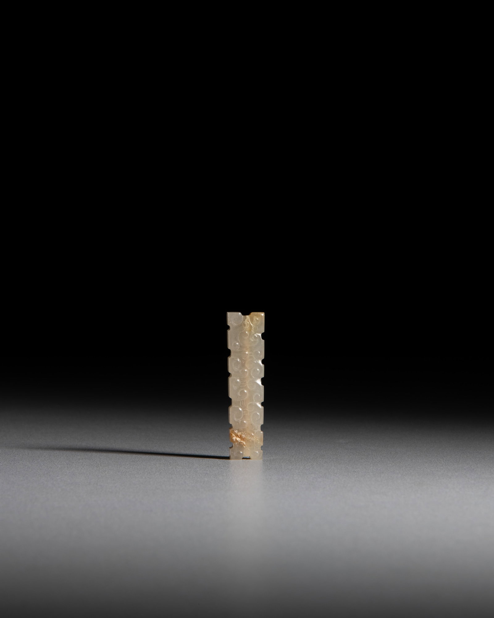 A RARE JADE RECTANGULAR BEAD WITH INTRICATELY CARVED SCROLLING CLOUD MOTIFS 春秋: A RARE JADE RECTANGULAR BEAD WITH INTRICATELY CARVED SCROLLING CLOUD MOTIFS 春秋 白玉带沁色勾云纹扁勒 China, The Spring and Autu