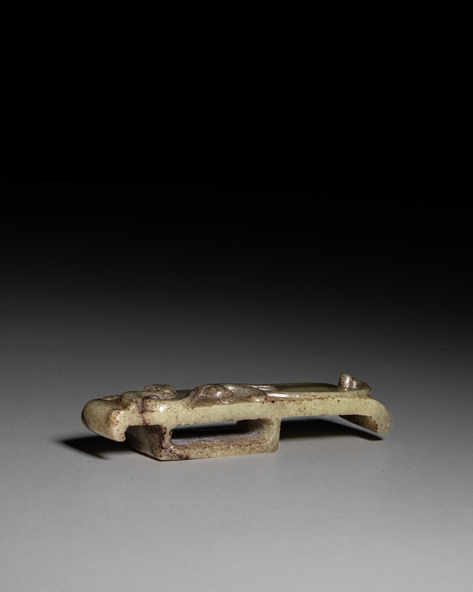 A CELADON JADE SWORD SLIDE CARVED WITH A CHILONG MOTIF 汉代 青玉带: A CELADON JADE SWORD SLIDE CARVED WITH A CHILONG MOTIF 汉代 青玉带黑棕沁色高浮雕螭龙纹玉剑璏
