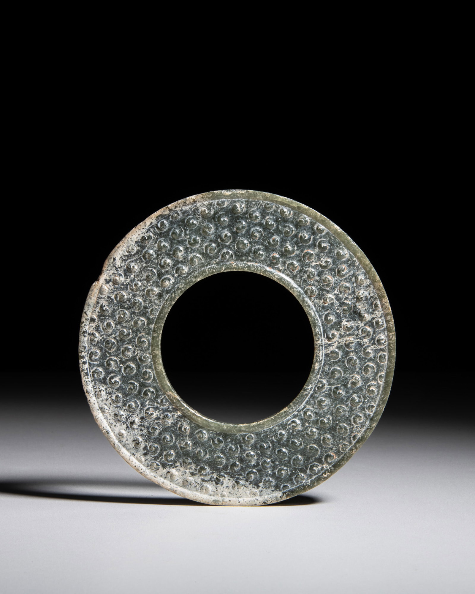 A FINE AND RARE PALE CELADON JADE 'GRAIN' HUAN DISC China, Han dynasty (206BC – 220AD) (1 of 3)