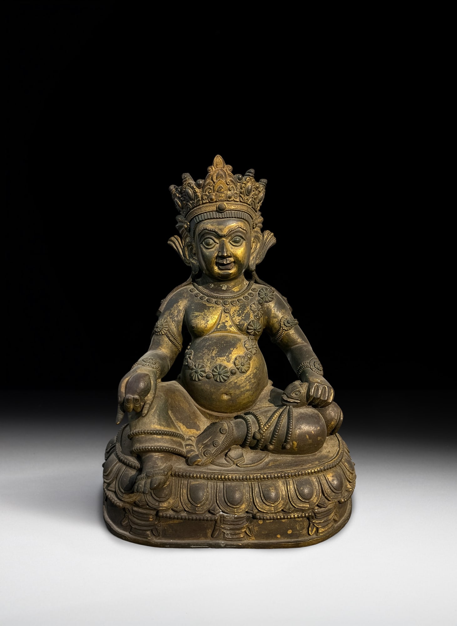 A GILT BRONZE SEATED JAMBHALA 清代 西藏 铜漆金黄: A GILT BRONZE SEATED JAMBHALA 清代 西藏 铜漆金黄财神坐像 Tibet, Qing dynasty Seated in lalitasana on a lotus base, the corpulent