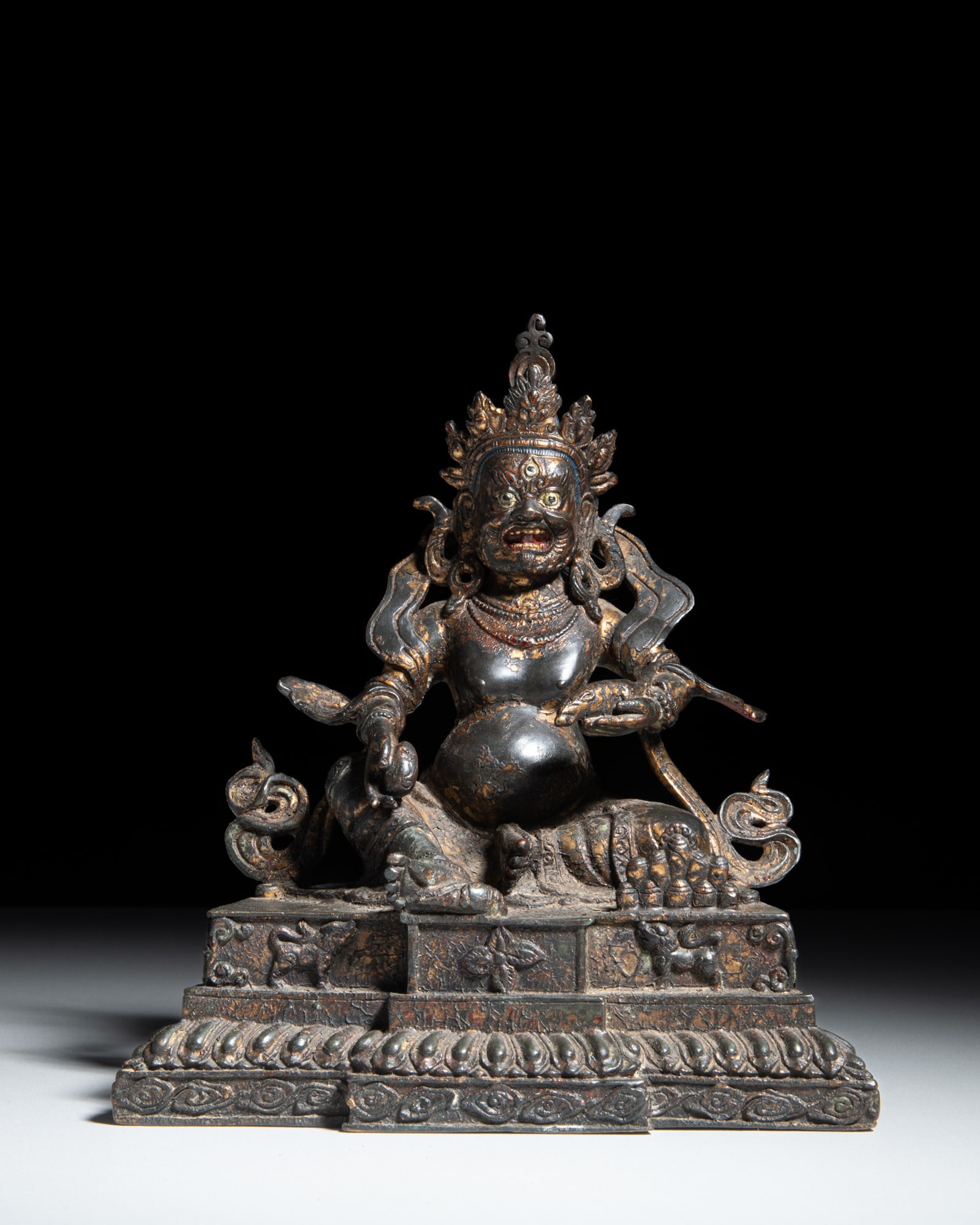 A LACQUERED BRONZE FIGURE OF JAMBHALA 民国 黄财神六字: A LACQUERED BRONZE FIGURE OF JAMBHALA 民国 黄财神六字箴言坐像 Sino-Tibet, Republic period Seated upon a double-tiered base, the lower 