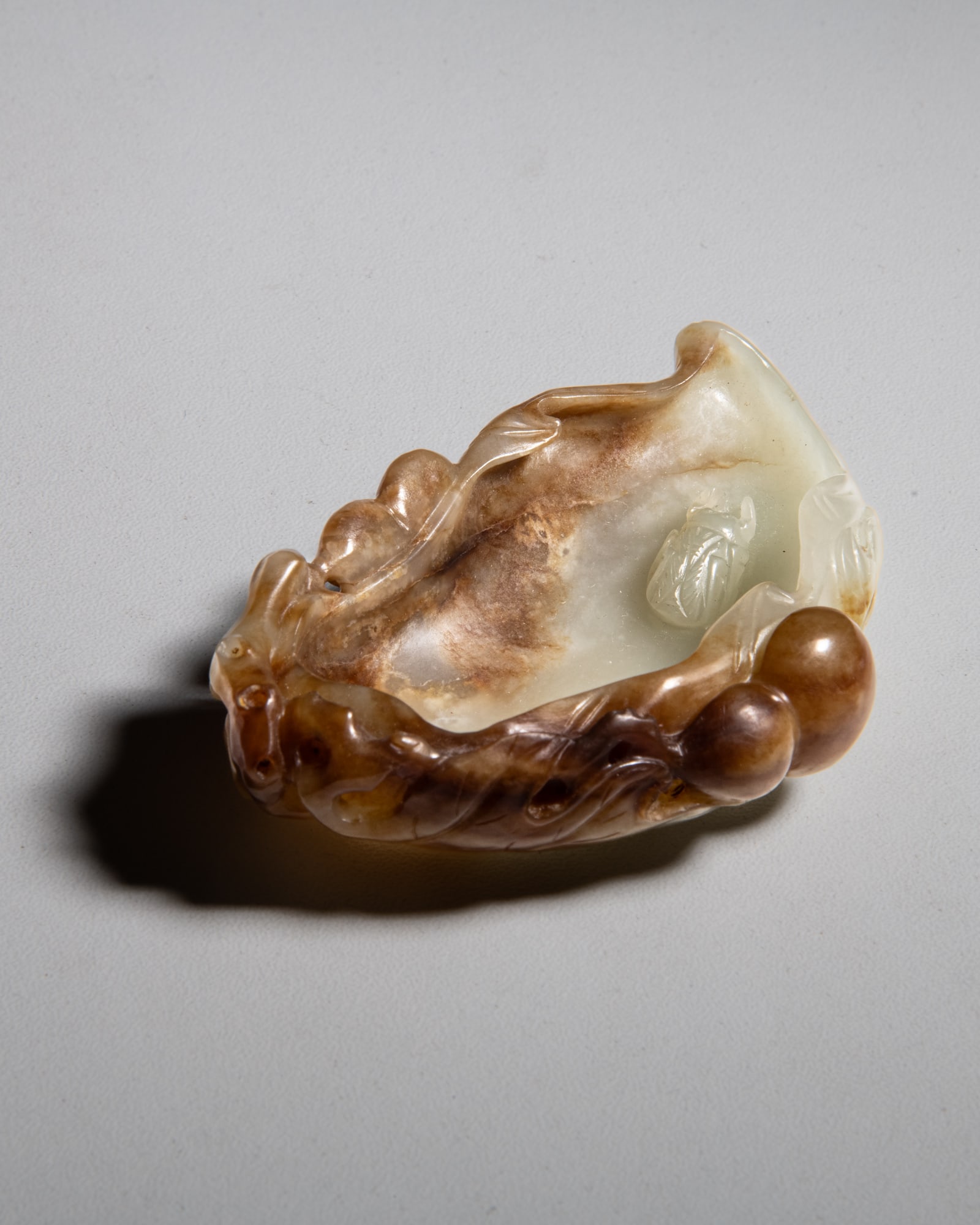A RETICULATED PALE AND RUSSET JADE LEAVE SHAPED BRUSH WASHER 20世纪 白玉: A RETICULATED PALE AND RUSSET JADE LEAVE SHAPED BRUSH WASHER 20世纪 白玉巧雕叶形笔添 China, 20th century L.8.9cm Provenance: Malaysian Chine
