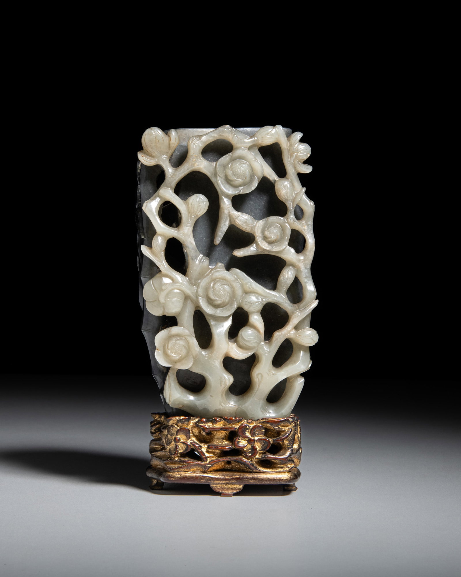 A RARE BLACK AND WHITE JADE 'THE THREE FRIENDS OF WINTER' VASE AND A CARVED WOODEN STAND 清: A RARE BLACK AND WHITE JADE 'THE THREE FRIENDS OF WINTER' VASE AND A CARVED WOODEN STAND 清代 19世纪 带木座 黑白玉透雕岁&#