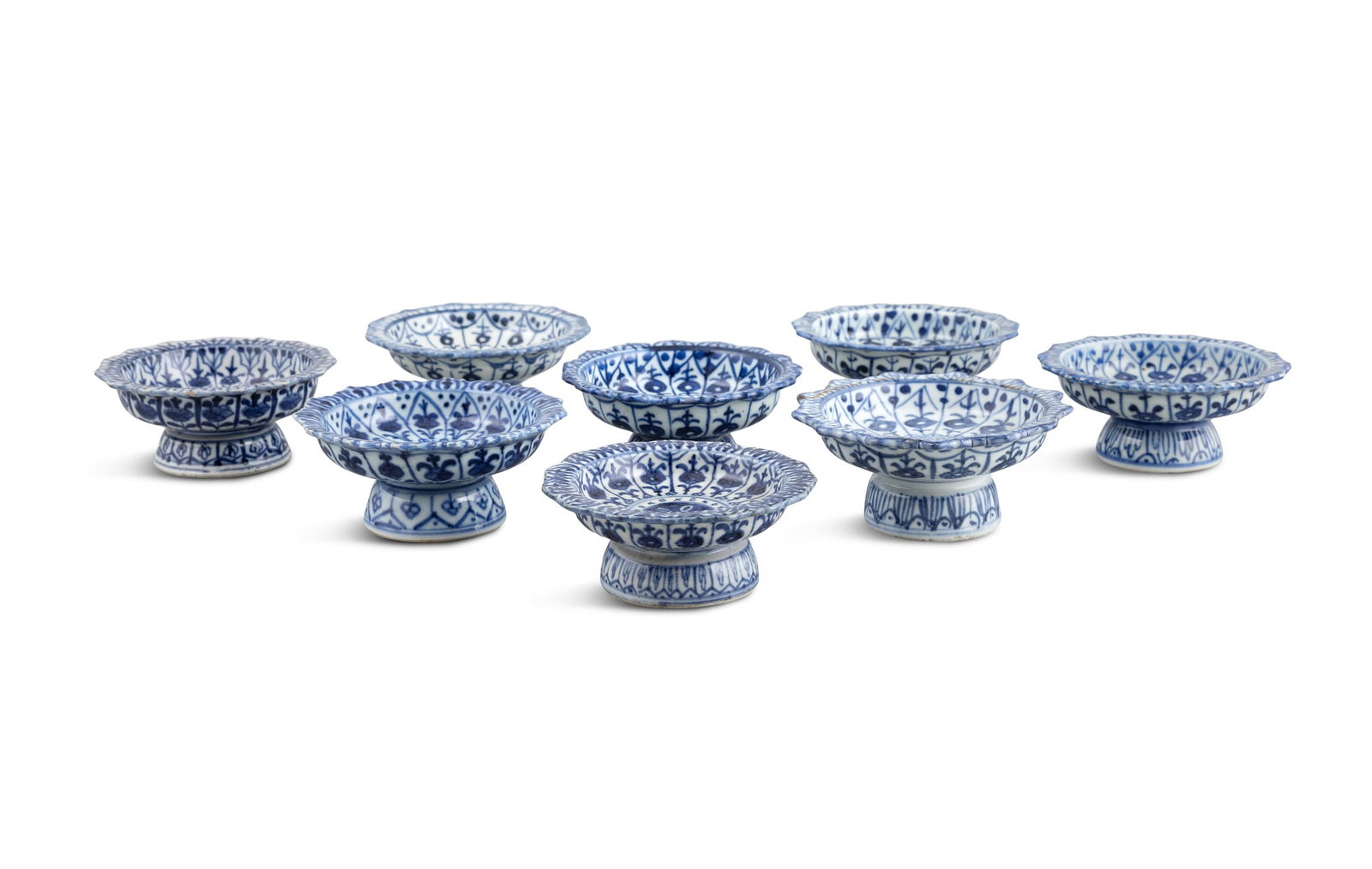 A COLLECTION OF EIGHT BLUE AND WHITE LOBED 'FLORAL' STEM STANDS 清代 青花: A COLLECTION OF EIGHT BLUE AND WHITE LOBED 'FLORAL' STEM STANDS 清代 青花花纹高足托盘一组八件 China, Qing dynasty D.