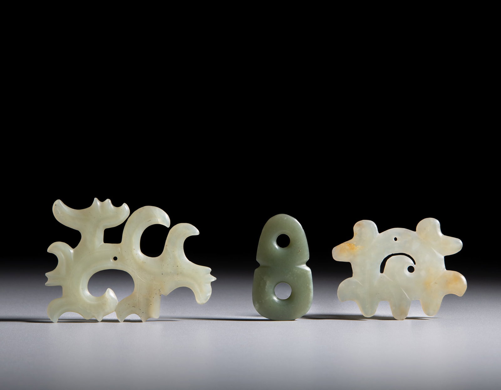 TWO PALE CELADON SCROLL CLOUD-SHAPED JADE PENDANTS AND A CELADON JADE “DOUBLE HUAN” (1 of 1)